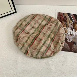 Detailed close-up of beige plaid beret featuring vintage distressed patterns and soft texture