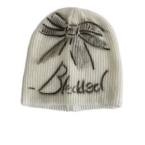 Chic cream white knitted beanie featuring black spray paint bow and graffiti script design