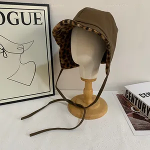 Detailed view of dark brown leather winter hat with leopard print faux fur lining and earflaps