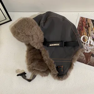 Detalle de gorro de aviador con forro grueso de piel sintética marrón y costuras naranjas