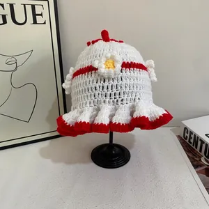 Close-up of handmade white crochet hat with red ruffled edges and floral detail