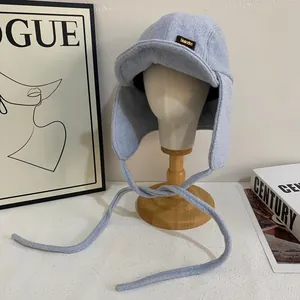 Dettaglio cappello aviatore in pile celeste con paraorecchie e toppa in pelle marrone