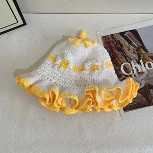 Close-up of white crochet bucket hat with yellow ruffled edges and floral accents