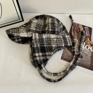 Détail de la chapka à carreaux avec cache-oreilles et longues lanières sur fond blanc