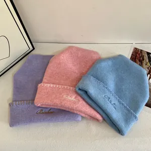 Detalle de gorros de punto con bordado Rainbow y costuras decorativas artesanales