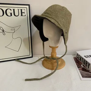 Close-up of herringbone fabric winter hat with earflaps and braided ties on mannequin
