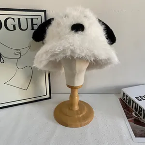 Close-up of white plush puppy bucket hat with long black ears on a wooden display stand