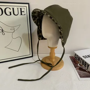 Dark green leather trapper hat with leopard print fur lining and earflaps for winter