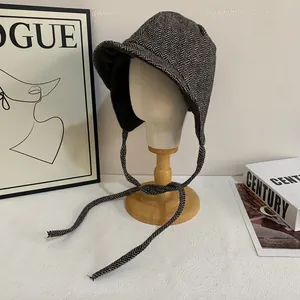 Detail shot of winter trapper hat featuring classic grey herringbone wool and long straps