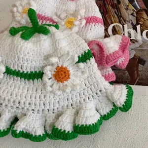 Detailed view of hand-woven white knit bucket hat with crochet flowers and wavy edges