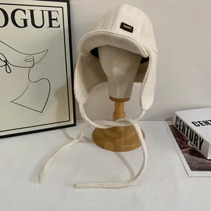 Dettaglio di un colbacco bianco crema in morbida texture felpata con toppa in pelle