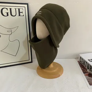 Vista detallada del gorro de forro polar verde oscuro con bordado en soporte de madera