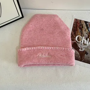 Detalle de gorro de punto rosa con bordado Rainbow y costura blanca en textura suave