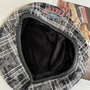Detailed close-up of plaid beret hat showing embroidery and warm fleece lining