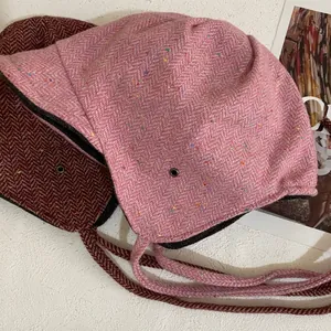 Detail of vintage wool trapper hats with ear flaps in pink speckled and dark red herringbone