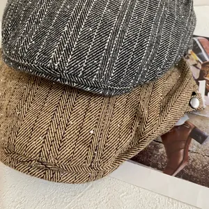 Close-up of herringbone newsboy caps in grey and khaki with subtle glitter and metal buttons
