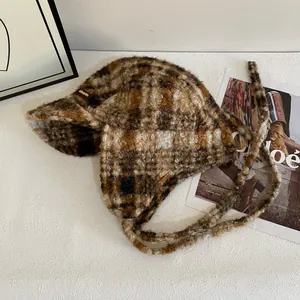 Gros plan du chapeau trappeur à carreaux marron avec texture polaire et étiquette en cuir