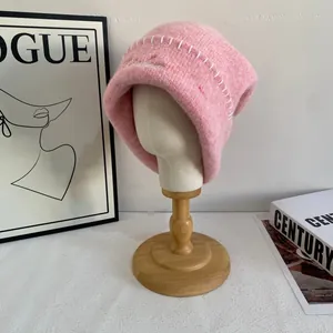 Detalle de gorro de punto rosa con costuras blancas, bordado en soporte de cabeza