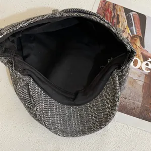 Detail view of the gray herringbone beret fabric with black lining and metal buckle