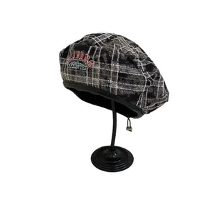 Retro plaid beret with red-blue embroidery and leather edge on a display stand