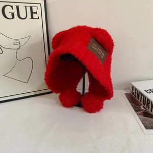 Dettaglio del cappello in pile rosso con etichetta in pelle e pompon coordinati