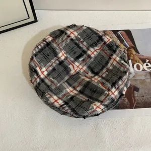 Detail van de geruite baret met gerafelde randen en rode stiksels op tweed stof