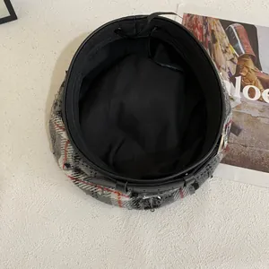 Detail van geruite baret met zwarte leren riem, metalen ankertje en binnenvoering