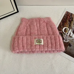 Dettaglio del cappello rosa lavorato a maglia con orecchie di gatto e patch a cartoni