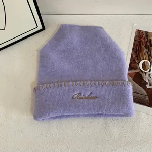 Detalle del gorro de punto morado con bordado Rainbow y costuras artesanales