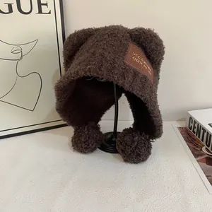 Dettaglio del tessuto teddy e delle orecchie da orso sul caldo cappello invernale con pompon
