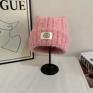 Dettaglio del berretto in maglia rosa con orecchie di gatto e toppa TV su supporto in metallo