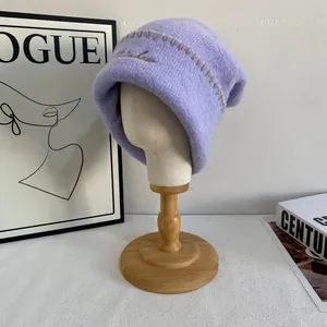 Detalle de la textura del gorro de punto lila con costuras marrones y bordado fino