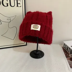 Dettaglio del berretto rosso scuro con orecchie da gatto in maglia soffice e patch TV