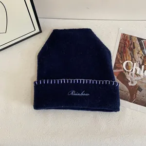 Detalle del gorro de punto azul marino con bordado Rainbow y costuras púrpuras