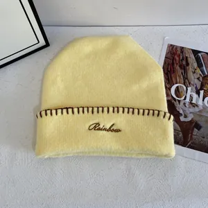 Detalle del gorro de punto amarillo claro con bordado Rainbow y bordes festoneados