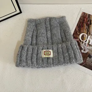 Dettaglio del berretto in maglia grigia con orecchie da gatto ed etichetta TV vintage
