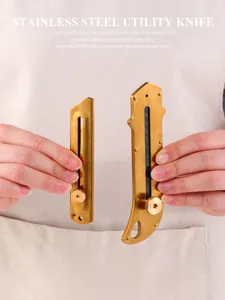 Detail of two vintage brass-colored utility knives with ergonomic stainless steel handles