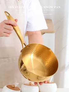 Close-up of golden 18/8 stainless steel snow pan with hammered texture and dual spouts