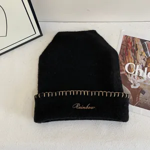 Detalle del gorro de punto negro con bordado Rainbow y costuras decorativas beige