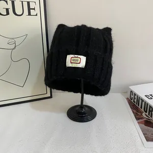 Dettaglio del berretto in maglia nera con orecchie di gatto e toppa TV retrò su stand