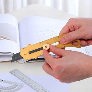 Brass utility knife tool with manual adjustment knob on a desk with stationery