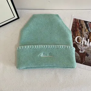 Detalle de gorro de punto verde menta con bordado Rainbow y costuras blancas de contraste