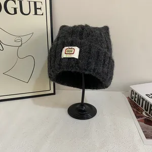 Dettaglio ravvicinato del berretto in maglia grigio scuro con orecchie di gatto e patch