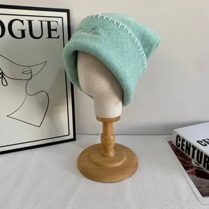 Detalle de gorro de punto verde menta con costuras blancas y bordado de calidad