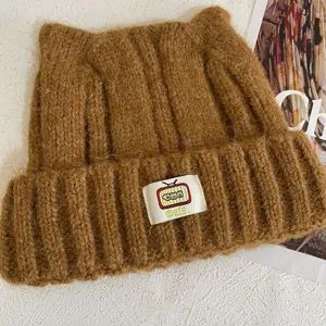 Texture dettagliata del berretto marrone con orecchie di gatto, toppa TV e lana soffice