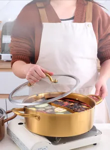 Detail view of dual-sided 304 stainless steel pot with golden handles on a gas stove