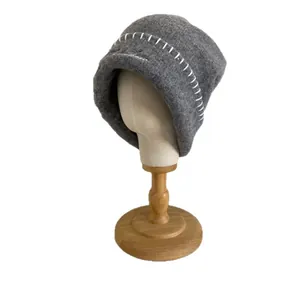 Gorro de punto gris oscuro con costuras blancas en soporte de madera