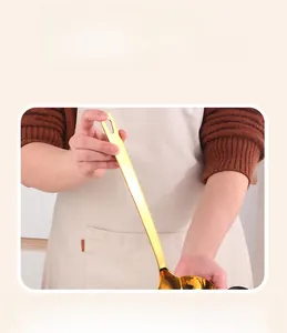 Macro detail of golden stainless steel ladle with extended anti-scald handle for kitchen