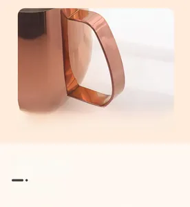 Detail of rose gold coffee pitcher with rounded handle and smooth polished finish