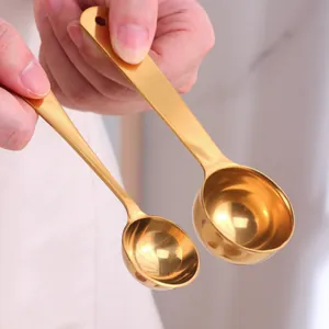 Mirror polished gold stainless steel measuring spoons set held by hand in warm setting